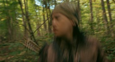 Blurred image of a person in a forest setting.