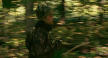 Person running through a blurred forest background.