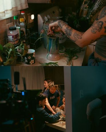 Person with tattoos arranging flowers in a vase on a cluttered kitchen counter.
