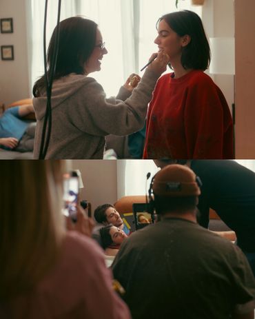 People applying makeup and filming a scene indoors.