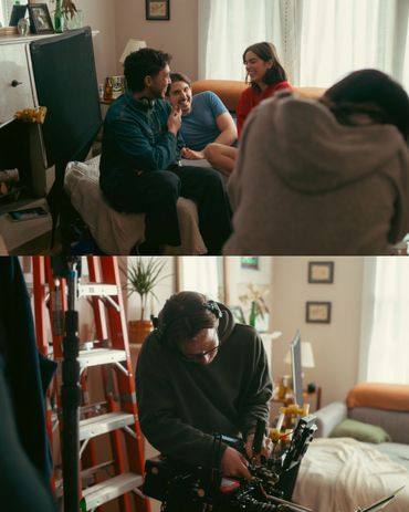 Friends chatting on a couch while a cameraman films in a cozy room.