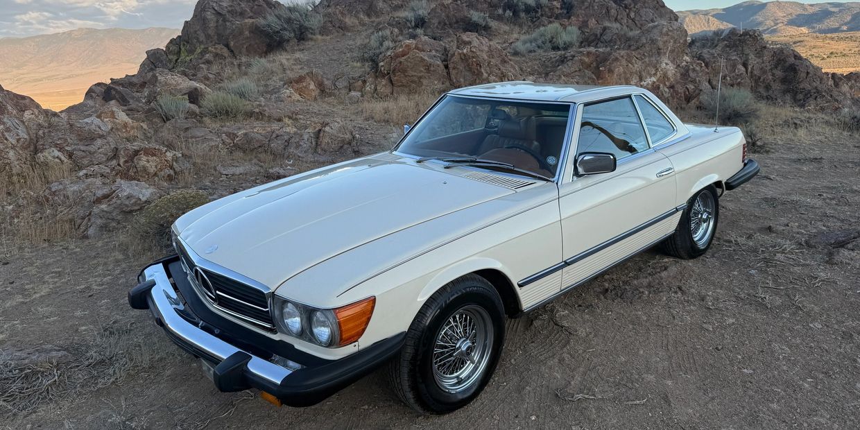 Classic white Mercedes-Benz car parked in rocky desert landscape.