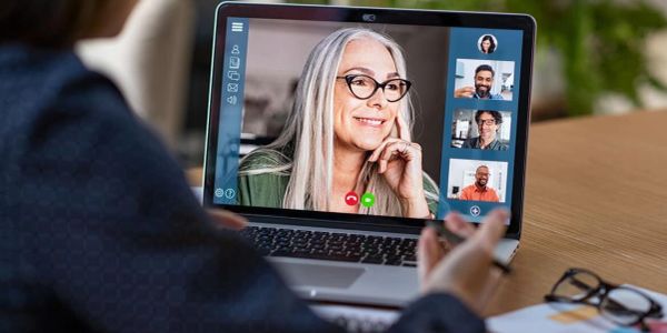Person video chatting with multiple people on a laptop.