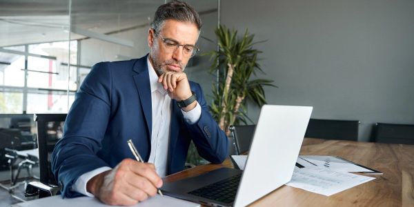 Businessman working intently at a desk with a laptop and documents.