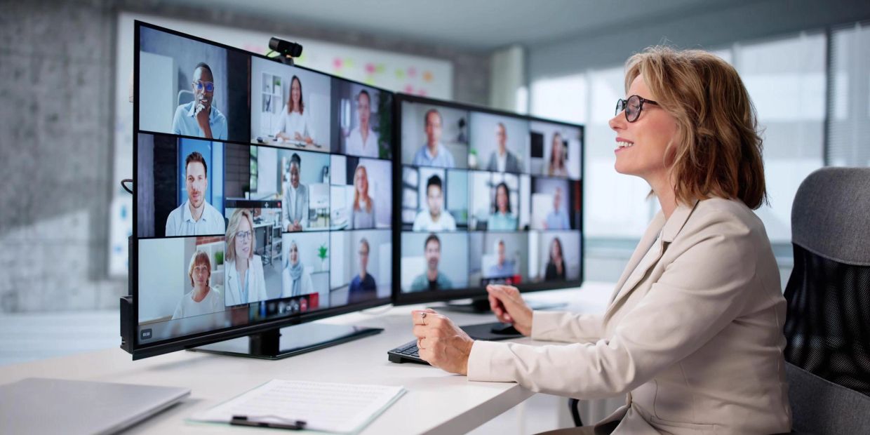 Woman participating in a video conference with multiple people.