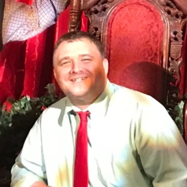 Man smiling in a festive setting with red tie