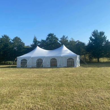 White event tent set up on a grassy field.