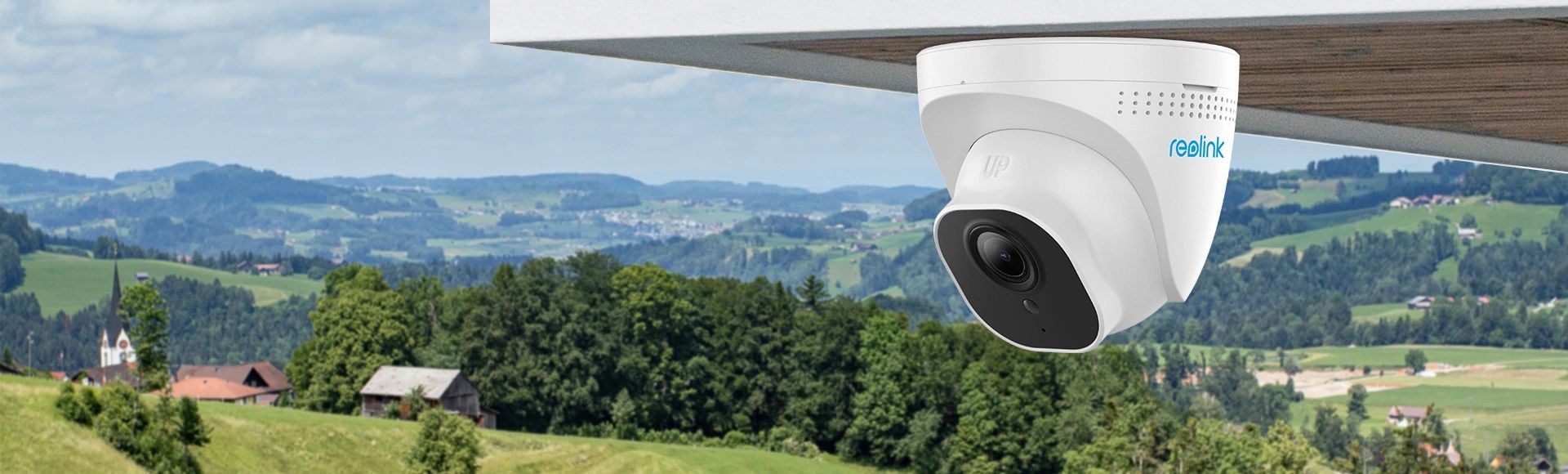 White security camera mounted outdoors overlooking a green countryside.