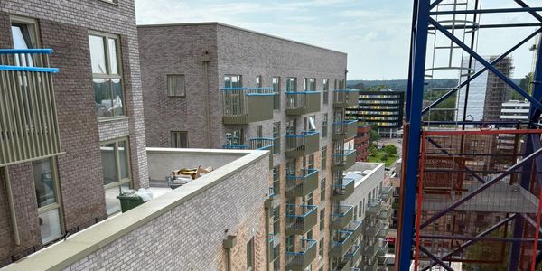 View of modern apartment buildings with balconies and a construction crane.