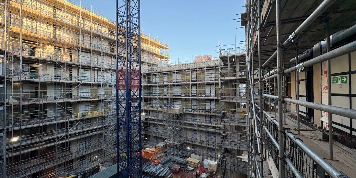 Large building under construction with scaffolding and crane.