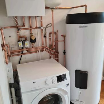 Laundry room with washing machine and water heater connected by copper pipes.