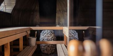 Interior of a wooden sauna with stone heater and bucket.