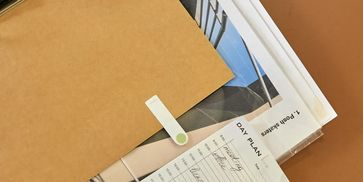 A brown folder with papers and a day plan sheet underneath.