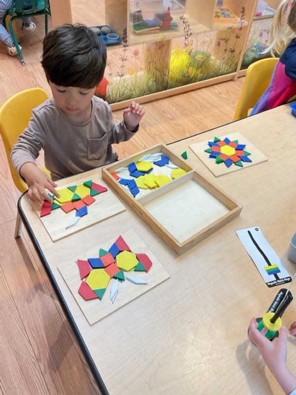 a child sitting at a table doing a tang-a-gram puzzle