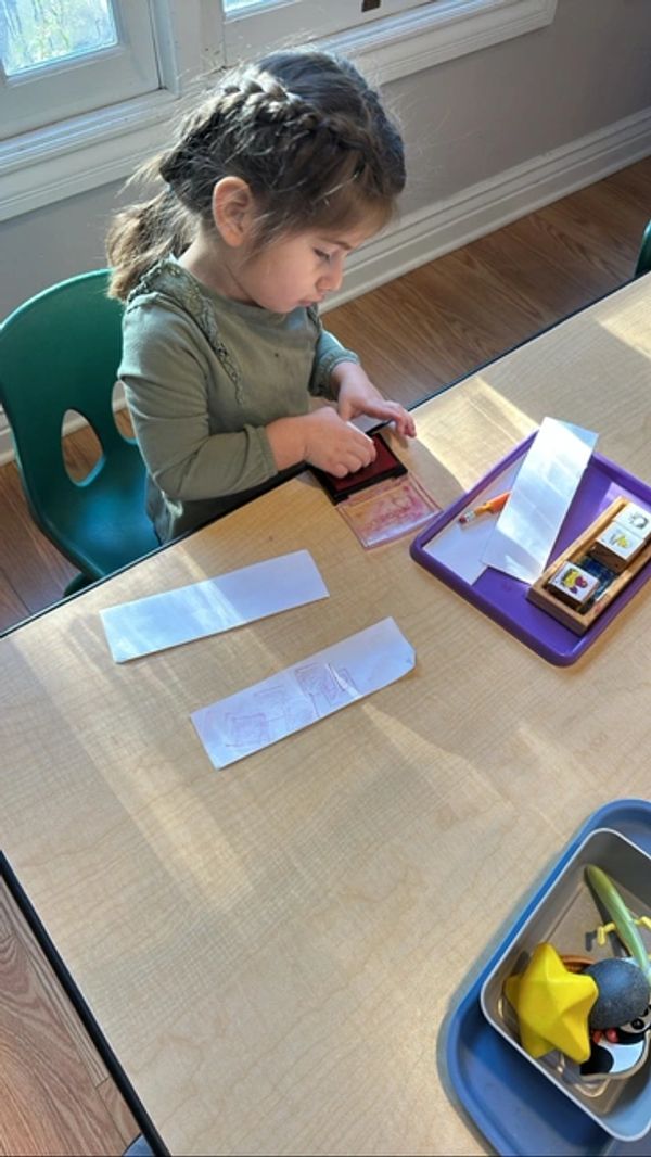 A child sitting at a table using stamps and a stamp pad