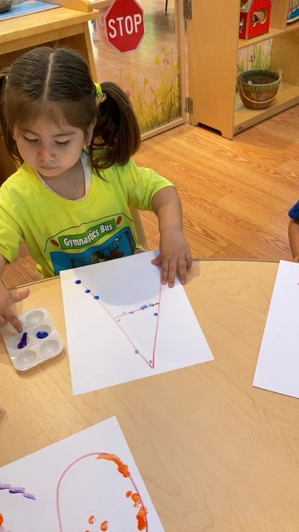 a child sitting at a table with the letter A in front of her