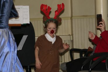 Child dressed as a reindeer with antlers and a red nose.
