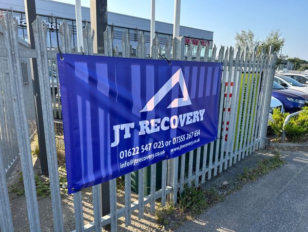 Blue banner with the logo of a vehicle recovery company on a fence