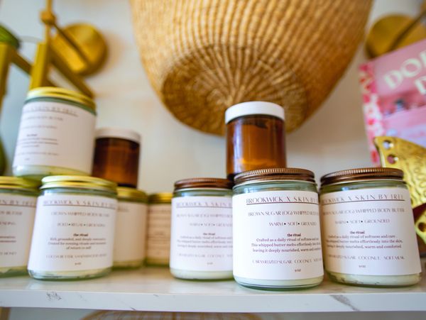Skincare products in glass jars displayed on a white shelf.