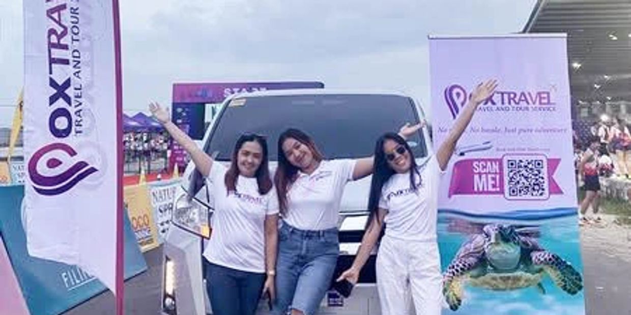 Three women posing happily in front of a van with travel company banners.