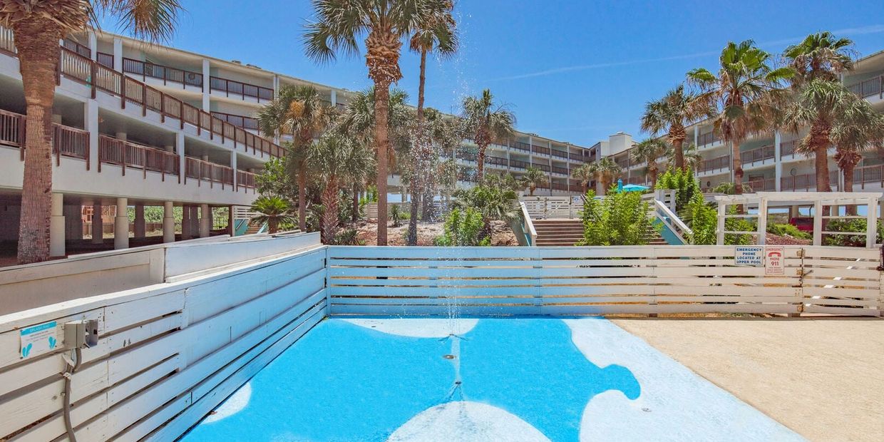 Empty motel courtyard with a small water feature and palm trees under a clear blue sky.