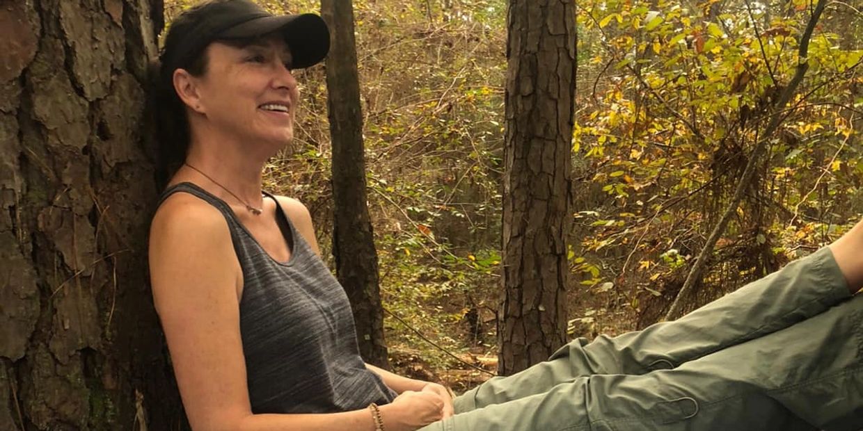 Woman relaxing against a tree in a forest.