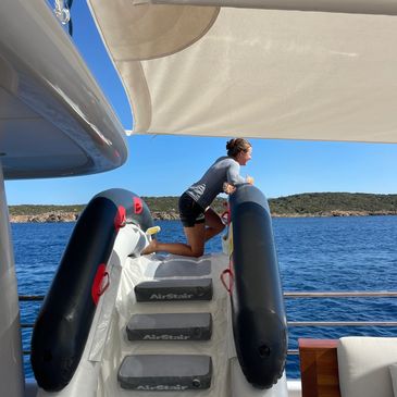 A woman relaxing on a boat ladder overlooking the water.