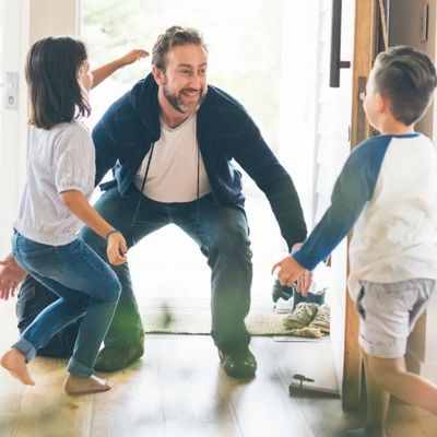 Father joyfully greeting his children at the door.