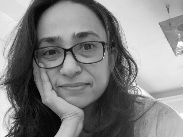 Woman with glasses resting her face on her hand.