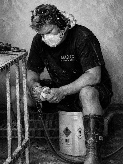 Worker in protective gear working on a piece of stone.