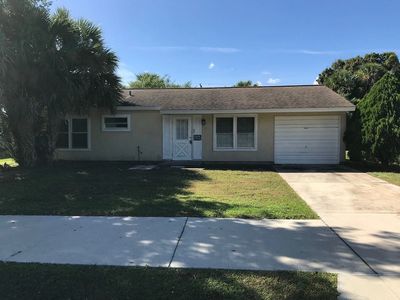 Single-story house with a garage and palm trees.