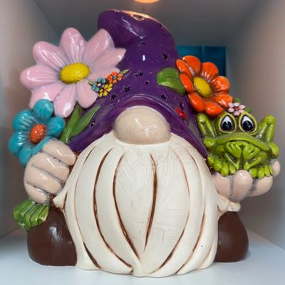 A colorful gnome figurine holding flowers and a small green creature.