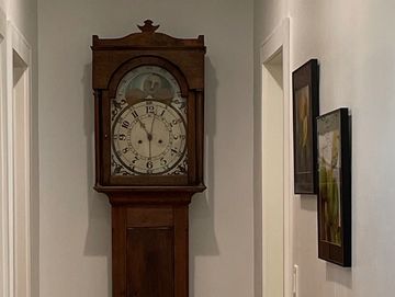 An antique long case clock at the end of a hallway.