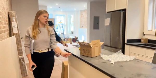 Woman inspecting a kitchen counter while holding papers.