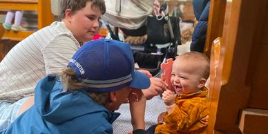 A baby happily interacts with two boys in a cozy indoor setting.