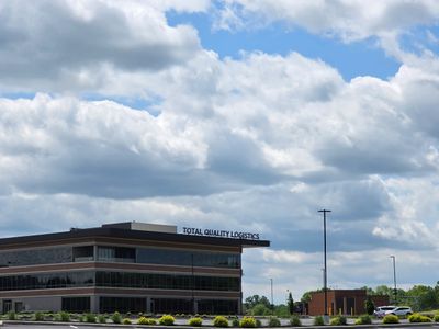 Modern office building under a partly cloudy sky with a Total Quality Logistics sign.