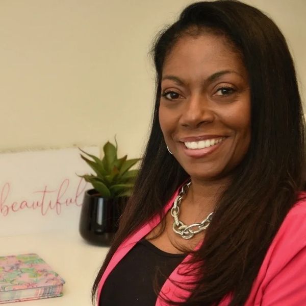 Smiling woman in a pink blazer with a silver necklace.