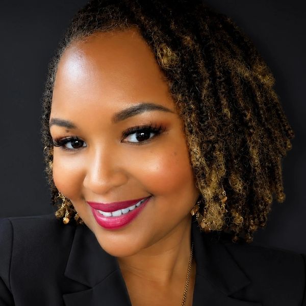 A smiling woman with curly hair and bright lipstick.