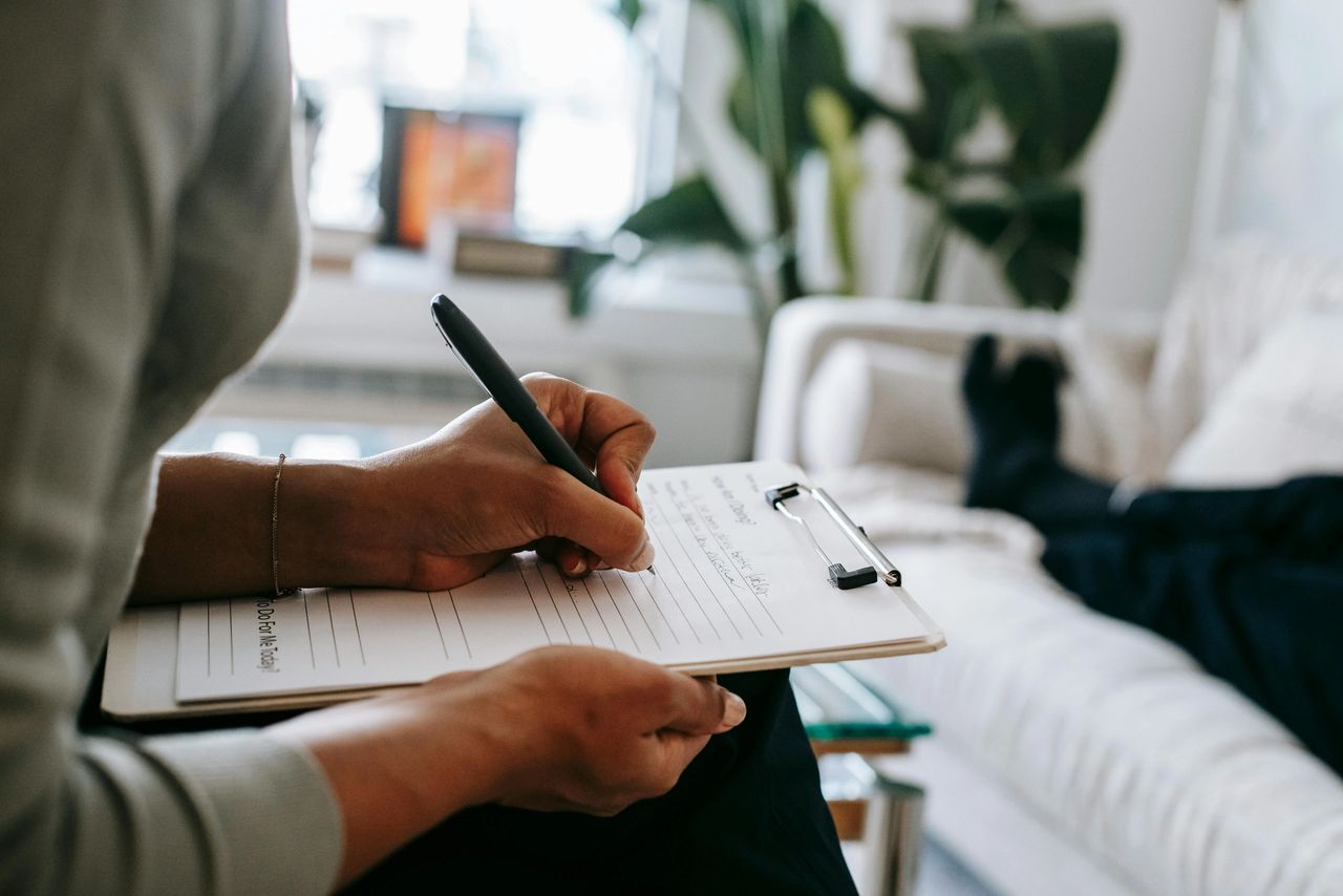 a person writing on a clipboard in a therapy session