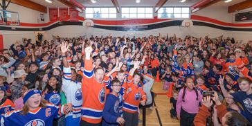 Large crowd of enthusiastic hockey fans in a gymnasium.