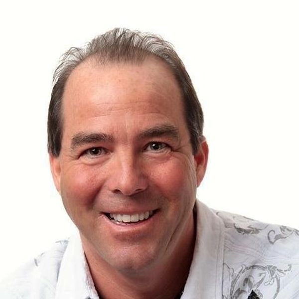 Smiling middle-aged man in a patterned white shirt against a white background.