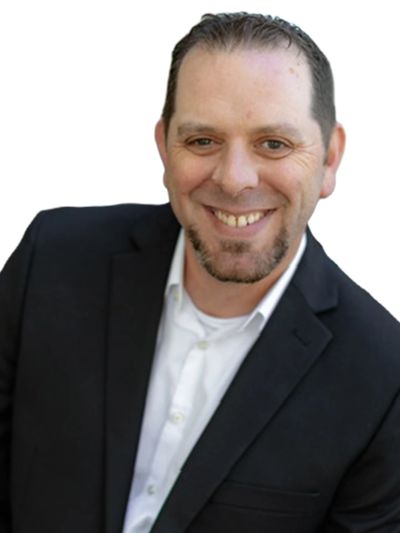Smiling man in a black suit and white shirt against a white background.