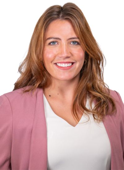 Smiling woman in a pink blazer and white blouse against white background.