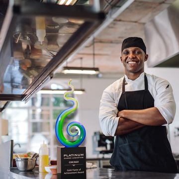 A smiling chef admires the art glass award he received, made by Awarding You, a recognition company.