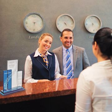 Concierge greets a customer at the counter, where a crystal service award by Awarding You sits.