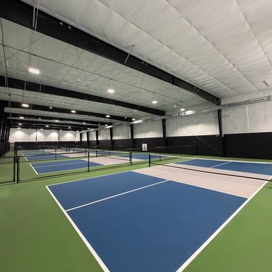 Indoor pickleball courts with blue playing surfaces and green borders.