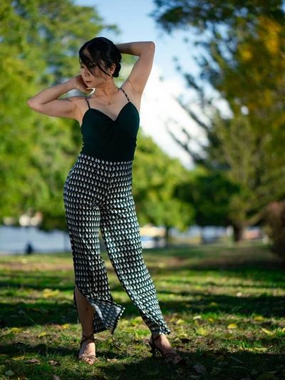 A woman posing gracefully in a patterned jumpsuit outdoors.