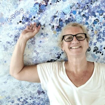 Smiling woman with glasses lies on a blue patterned surface.