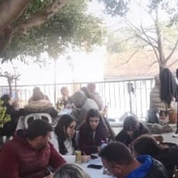 People gathered outdoors sharing a meal under trees.