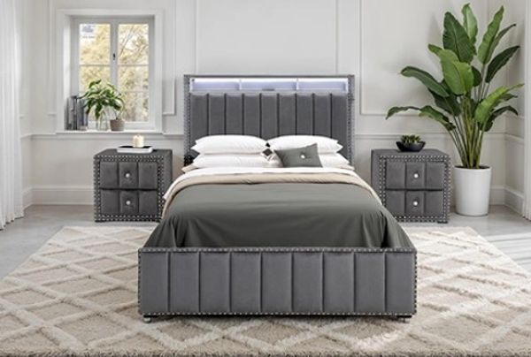 Modern gray bed with matching nightstands and indoor plants.